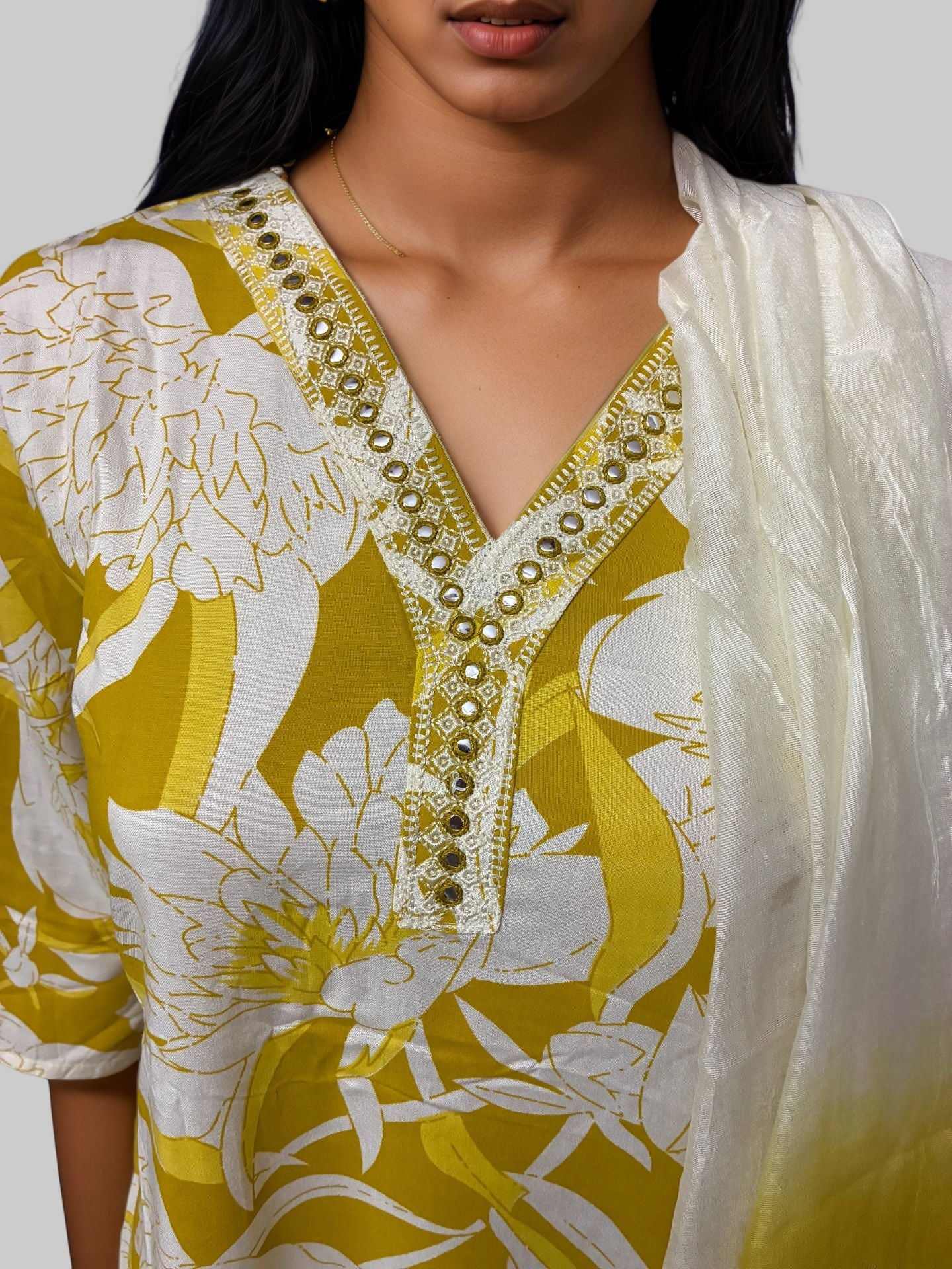 Woman wearing a yellow and white floral dress with intricate detailing.