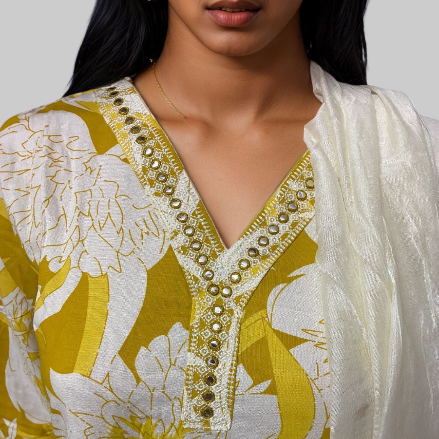 Woman wearing a yellow and white floral dress with intricate detailing.