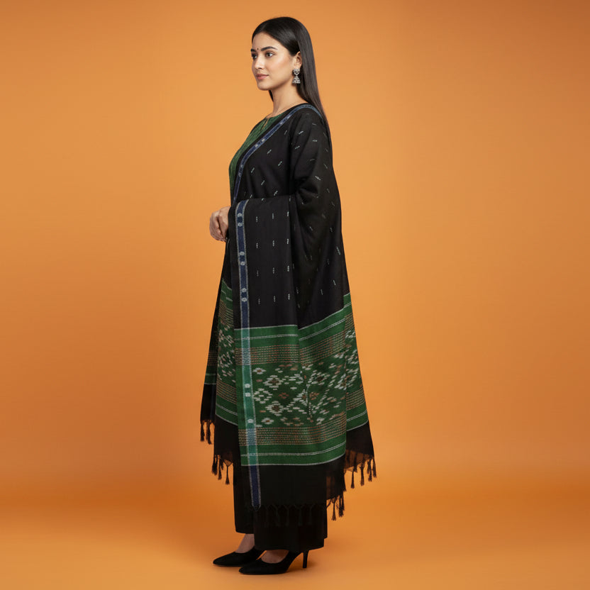 Woman wearing a green and black traditional outfit with a matching scarf on a gray background