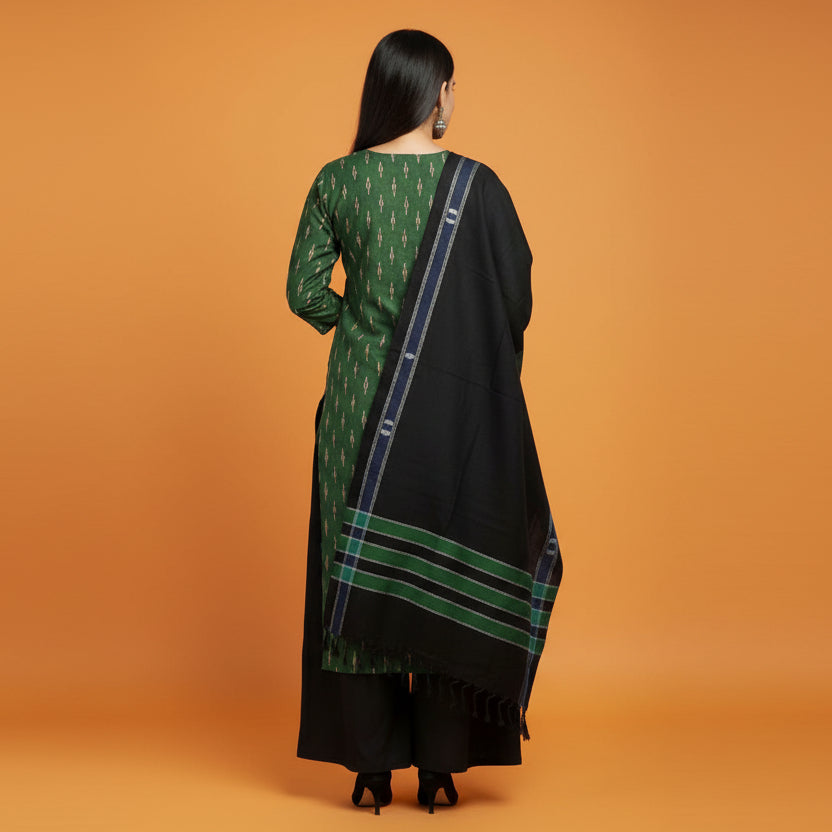 Woman wearing a green and black traditional outfit with a matching scarf on a gray background