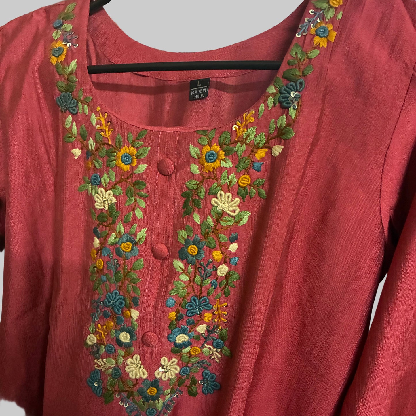 Red garment with floral embroidery on a reflective surface