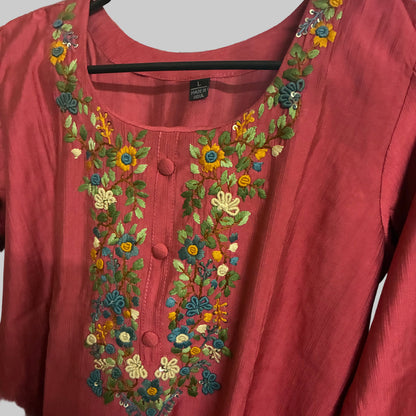 Red garment with floral embroidery on a reflective surface
