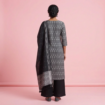 A woman modeling a traditional Indian outfit consisting of a black and gray patterned kurta, black pants, and a matching dupatta, set against a plain light gray studio background.