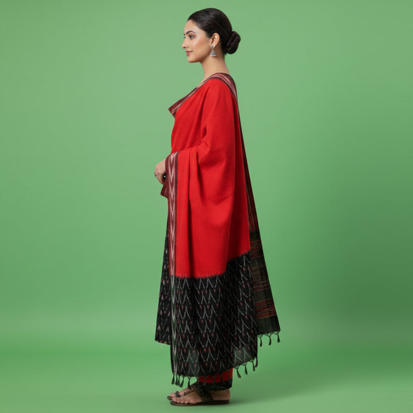 Woman wearing a red and black traditional outfit with a patterned shawl on a gray background