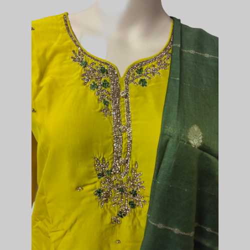 Yellow outfit with green dupatta on a mannequin against a white background